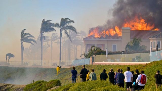Pessoas observam casa queimando