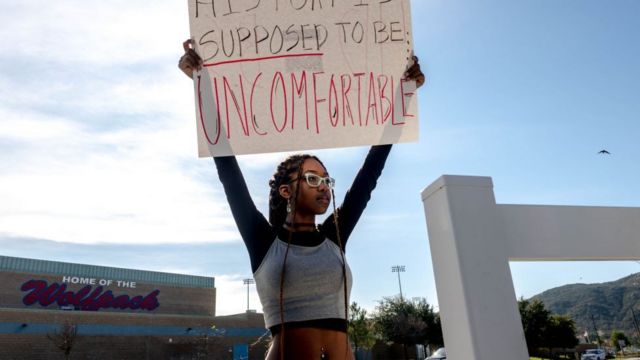 Una estudiante con un letrero a favor de la teoría crítica de la raza.