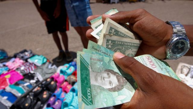 Hombre con bolívares y dólares en la mano.