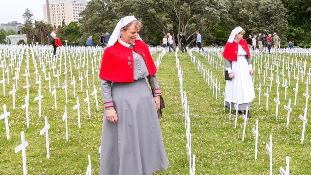 Tracey (L) and Katherine Meeten, dressed as nurses, look at crosses in the Fields of Remembrance in Auckland, New Zealand
