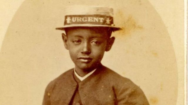 Foto do do príncipe Alemayehu usando um chapéu com o nome do navio HMS Urgent