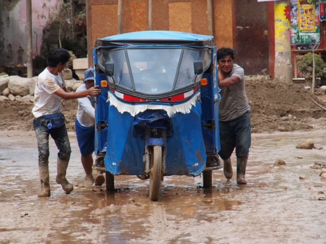 Tres hombres empujan un mototaxi en Lima.