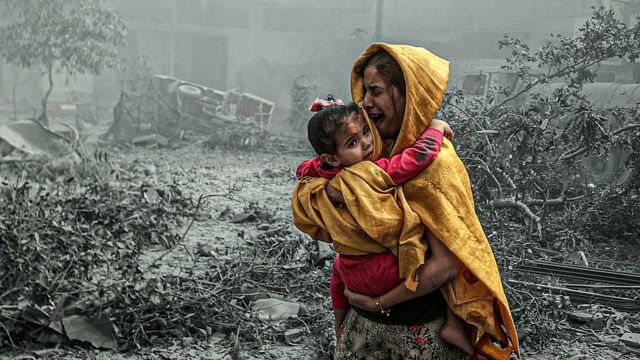 Madre con un niño huyendo de bombardeos en Gaza