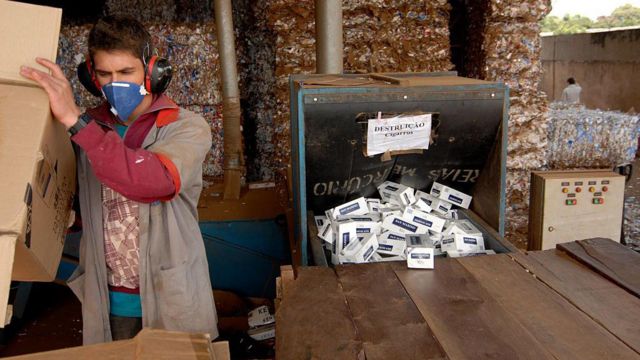 Un operario destruye cajas de cigarrillos.