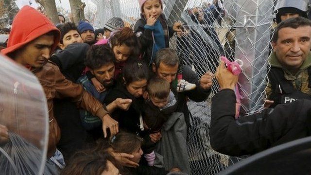 A Syrian refugee family prepares to cross the Greek-Macedonian border through a metal border fence near the village of Idomeni