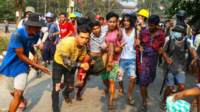 Manifestantes cargan a un herido durante las protestas en Yangon en marzo de 2021.