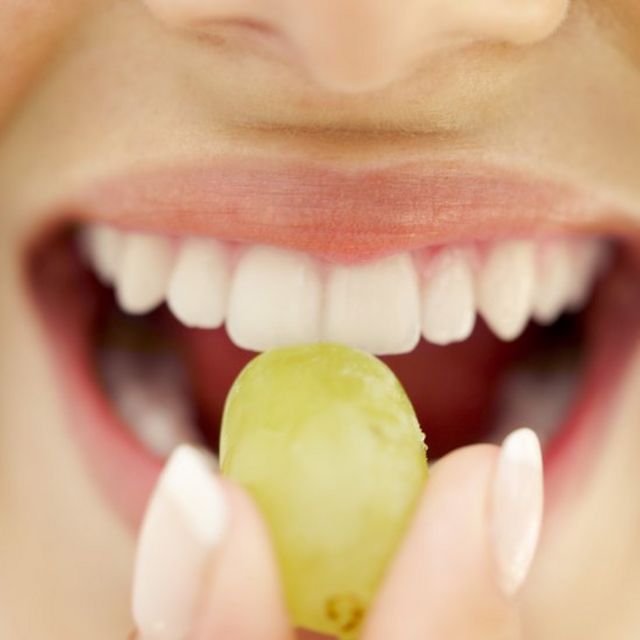 Mujer comiendo una uva.