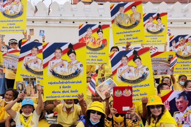 Supporters of Thailand"s King Maha Vajiralongkorn and Queen Suthida hold placards as they gather before a religious ceremony, at The Grand Palace in Bangkok, Thailand, November 1, 2020