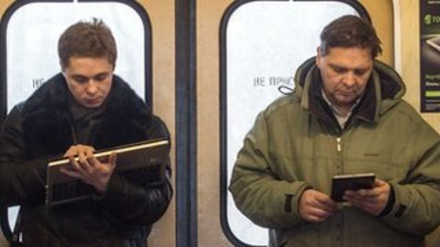 Pasażerowie moskiewskiego metra czytają w mediach cyfrowych.