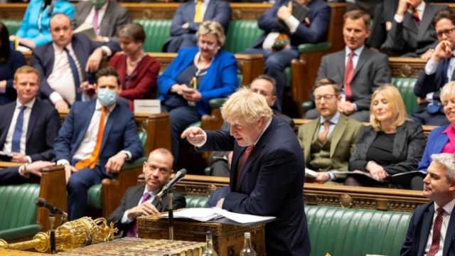 Johnson gesticula enquanto discursa, rodeado por parlamentares sentados