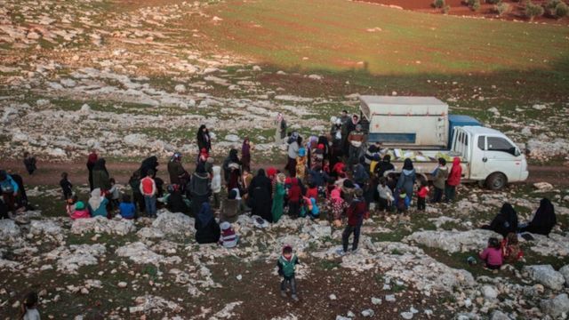Displaced Syrians from Idlib province receive food aid from a truck