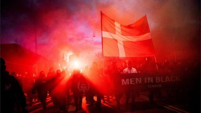 Manifestantes com uma grande bandeira da Dinamarca cruzam a capital Copenhague