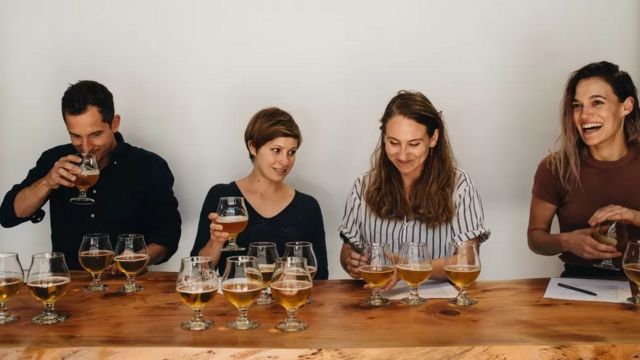 Grupo de pessoas reunidas numa mesa bebendo cerveja em taças