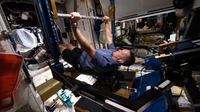 Homem branco astronauta fazendo exercicio na ISS