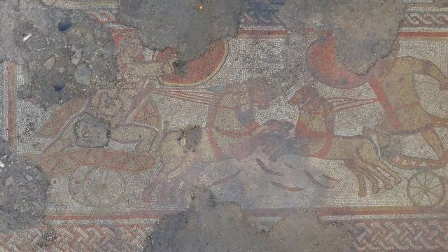 Mosaico romano com pedaços faltando mostra homens em bigas