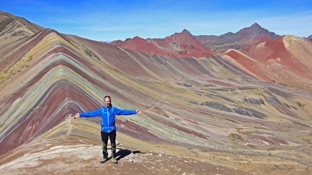 Turista parado de espaldas a la Montaña de los Siete Colores.