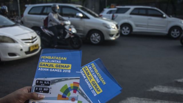 Petugas Badan Pengelola Transportasi Jabodetabek (BPTJ) melakukan sosialisasi kepada pengguna kendaraan bermotor pada hari pertama uji coba perluasan kawasan ganjil genap di persimpangan Pancoran, Jakarta, Senin (2/7), guna mendukung kelancaran arus lalu lintas pada penyelenggaraan Asian Games 2018.