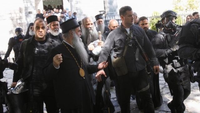 Security personnel escort Patriarch Portfirije and Bishop Joanikije outside a monastery in Cetinj