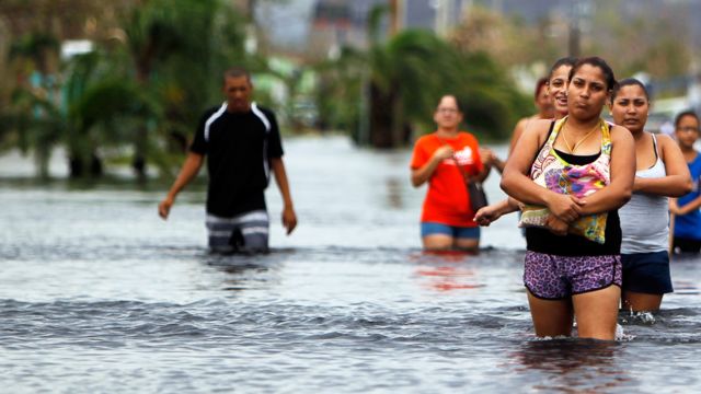 Personas caminando en un calle con el agua por las rodillas en Puerto Rico luego del Huracán María