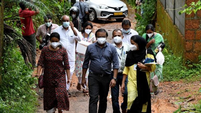 Membros de uma equipe da Faculdade de Medicina de Kozhikode caminham pelas ruas da vila de Maruthonkara, em Kerala, na Índia, com amostras para realizar testes sobre o vírus Nipah em laboratório