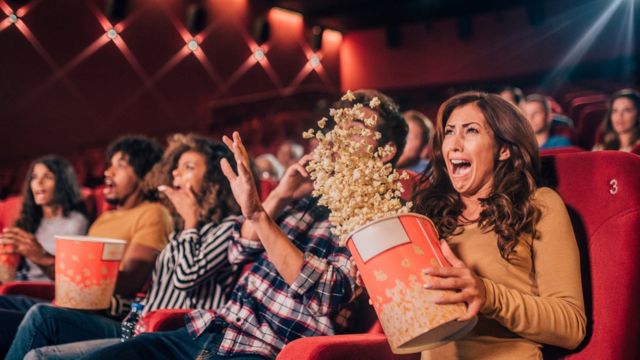 Personas en el cine viendo una película de miedo.