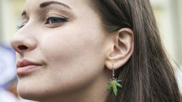 Mulher com brinco em formato de folha de maconha