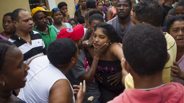 Los vecinos del barrio de Capotillo intentan consolar a la madre de las niñas que murieron cuando un desplazamiento de tierra impactó las paredes de su casa durante el paso del huracán Matthew.