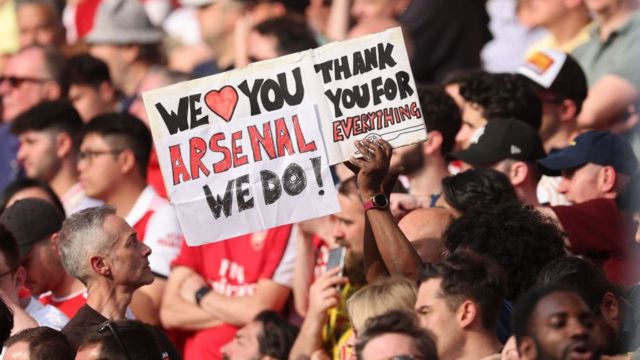 Arsenal fan holding up a 'we love you Arsenal we do' banner