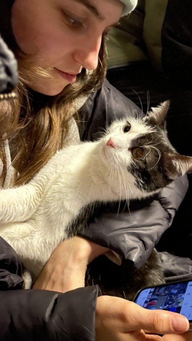 Yustyna Dusan sur son téléphone en tenant un chat.
