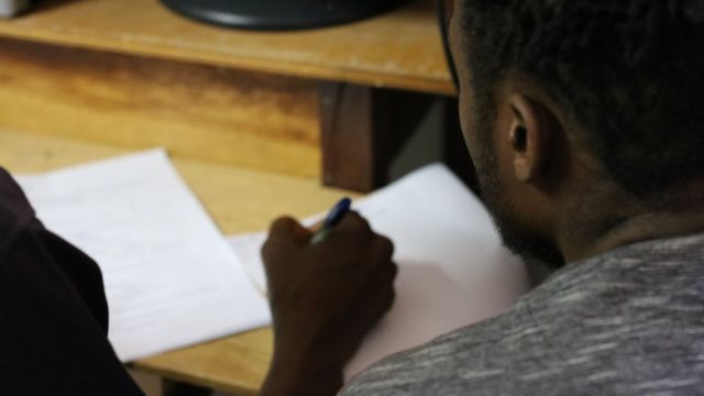 Haitiano sentado perto de documentos sendo assinados