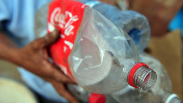 Homem segura garrafa plástica de 2 litros de coca-cola