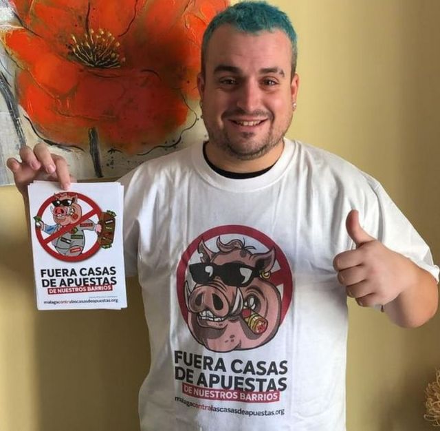 Santiago Caamaño con una camiseta y un panfleto en contra de las casas de apuestas en los barrios