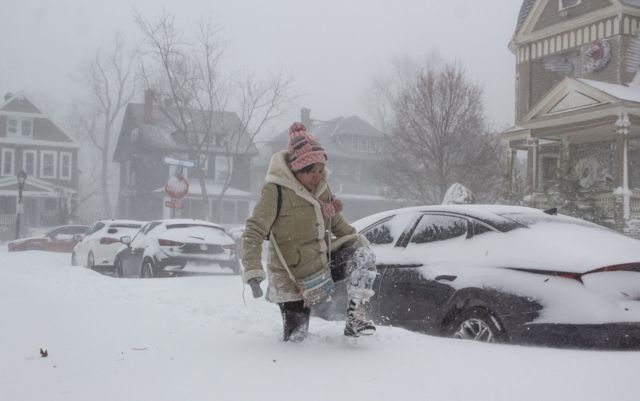 una mujer intenta caminar por la calle llena de nieve.