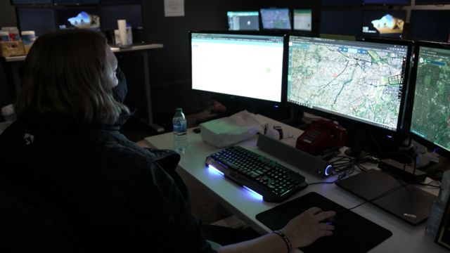 Ginger Ammon, analista ShotSpotter, em frente a três telas de computador que mostram mapas de Nova York