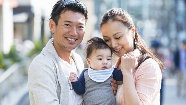 Casal japonês sorrindo com bebê no colo