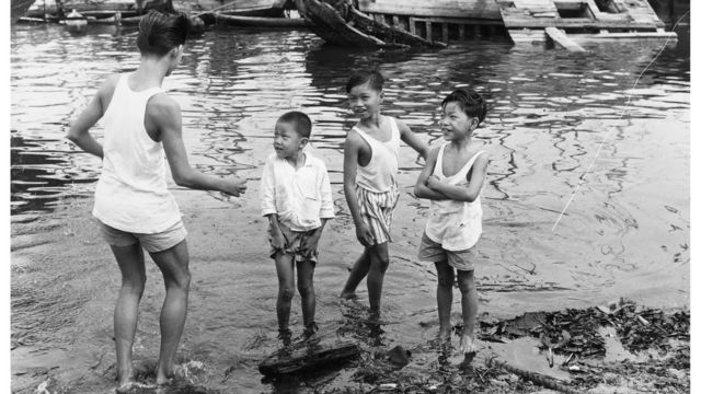 Crianças de Cingapura brincam no porto no início dos anos 1960