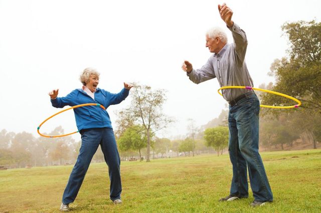 Elderly couple playing with hula hoops in park