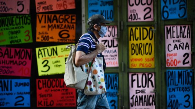 Un hombre camina frente a un comercio de alimentos en Venezuela.