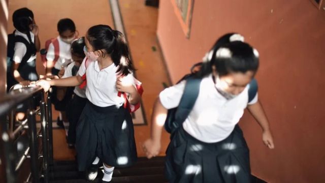 Crianças de máscara subindo escada