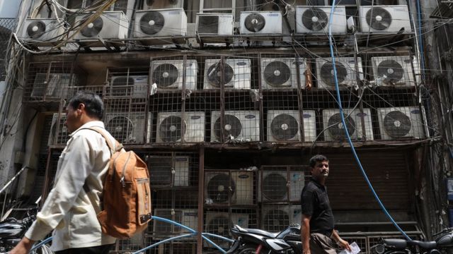 Parede coberta de aparelhos de ar-condicionado do lado de fora de um escritório, em Nova Déli.
