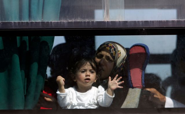 (من الأرشيف) امرأة وطفلتها تنظران من نافذة حافلة عند معبر رفح، على أمل العبور إلى مصر من قطاع غزة، فلسطين، يوليو/تموز 2014.