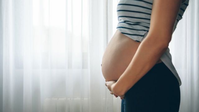 Mujer embarazada frente a la ventana.