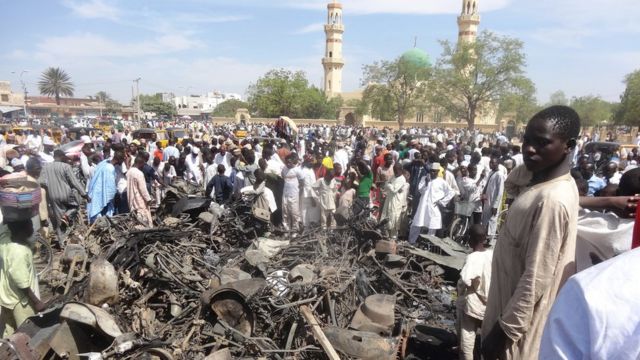 Decenas de personas observan una motocicleta quemada frente a la mezquita central de Kano, en el norte de Nigeria, el 29 de noviembre de 2014, después de un ataque suicid durante los rezos del viernes.