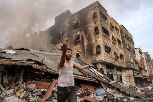 Homem em frente a prédio destruído