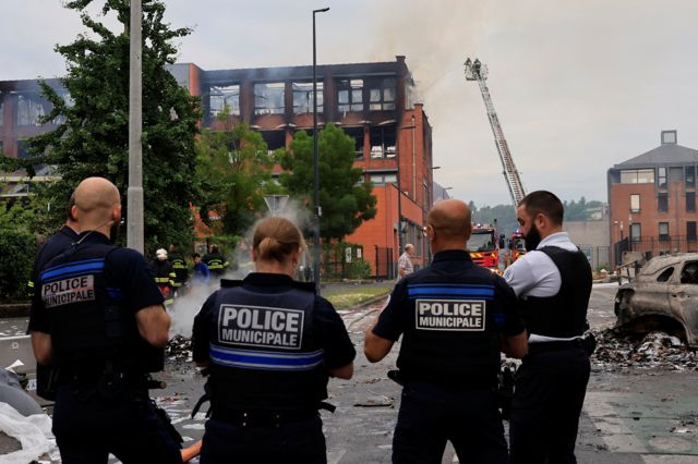 Cuatro policías miran la biblioteca quemada en una ciudad de Francia