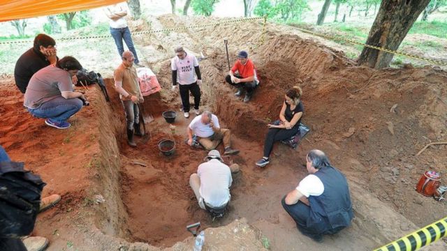 Homens e mulheres em uma escavação em busca de desaparecidos no Paraguai