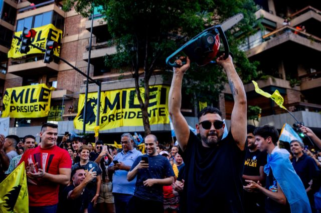 Votantes de Javier Milei, uno de ellos con una motosierra como símbolo de de los recortes que quiere hacer al Estado.