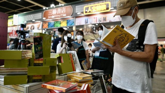香港书展一书摊上一位读者翻阅有关北京故宫的书籍（中新社图片20/7/2022）