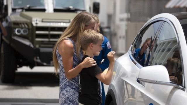 Karen Nyberg y su hijo se despiden de Doug Hurley, que va en un auto Tesla a la plataforma de lanzamiento.