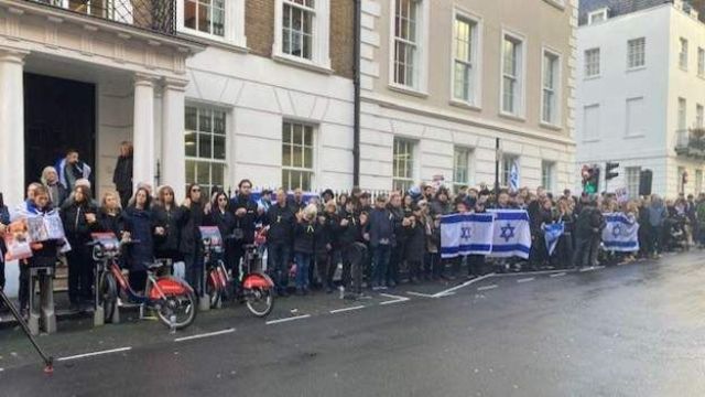 Pessoas com bandeiras de Israel em frente a um prédio londrino